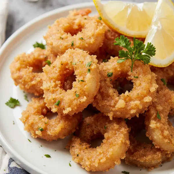 Close-up of golden fried shrimp with parsley and lemon.
