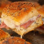 Ham and cheese sliders served on a platter with toppings