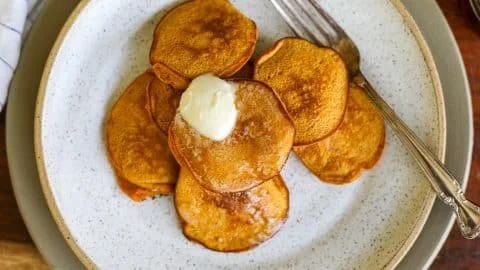 Plate of healthy sweet potato pancakes topped with syrup and fresh fruit