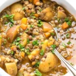 A bowl of easy lentil potato soup garnished with herbs