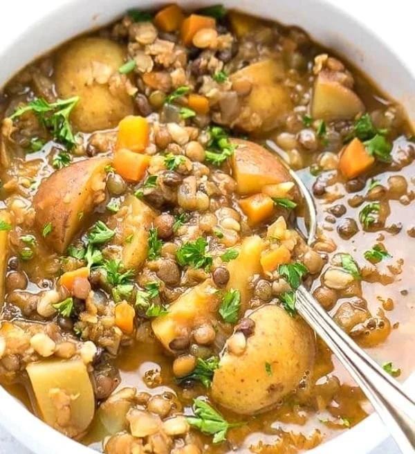 A bowl of easy lentil potato soup garnished with herbs
