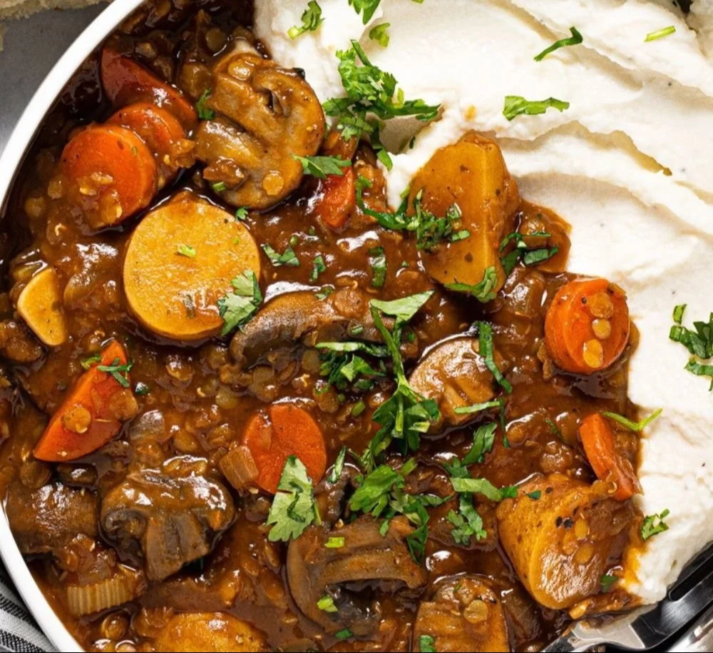 A bowl of vegan lentil and mushroom stew garnished with fresh herbs.